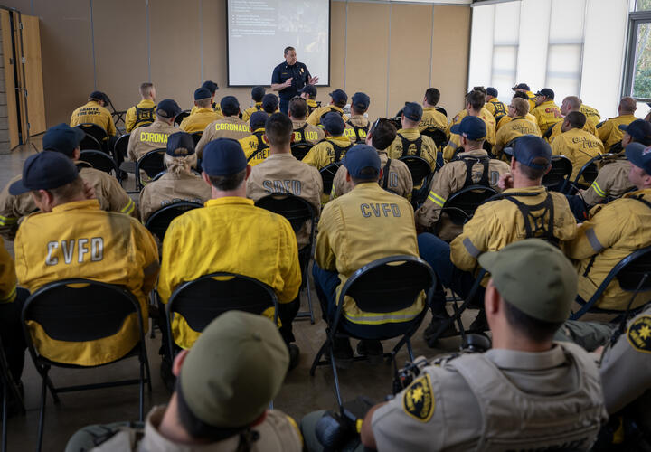 A large group of fire fighters participate in classroom training.