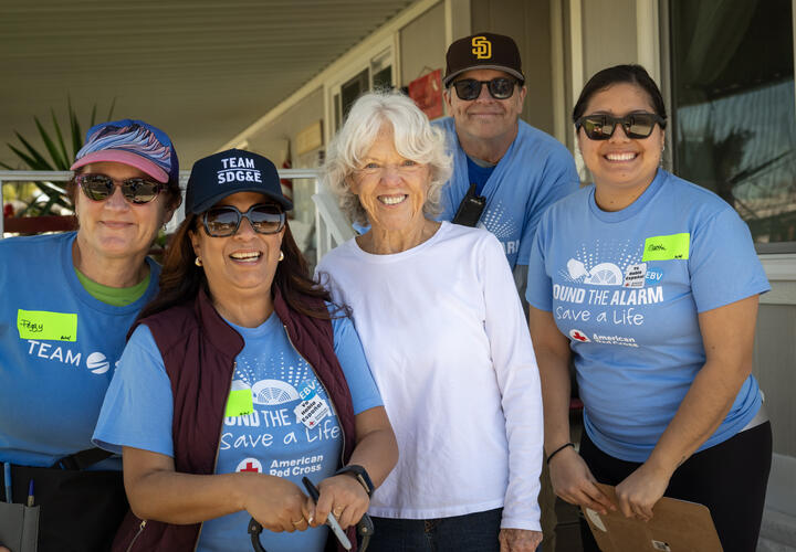 A group photo of SDG&E employees and a local oceanside resident