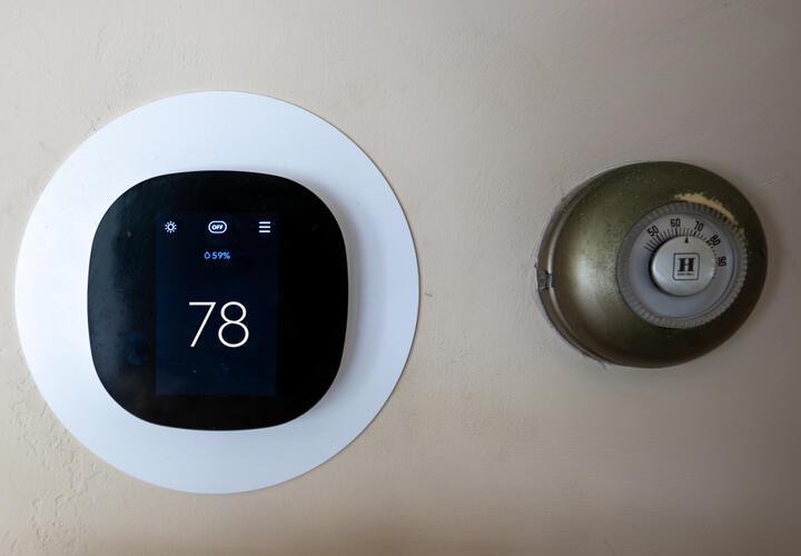 A photo of a modern thermostat, set to 78 degrees, alongside an older one.