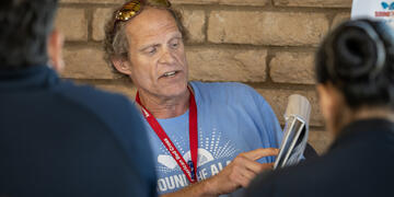 A male American red cross voulnteer demonstrates proper fire alarm installation techniques to new volunteers