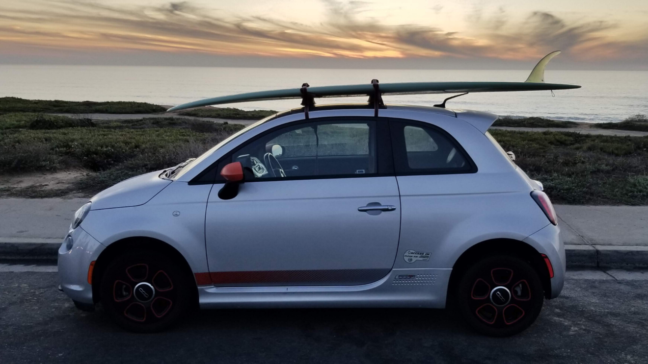 Clint driving his EV with a surf board strapped on top