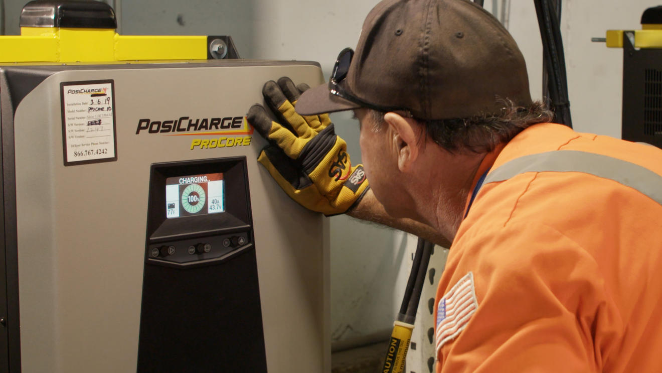 Port employee charging electric forklift at new charging station.