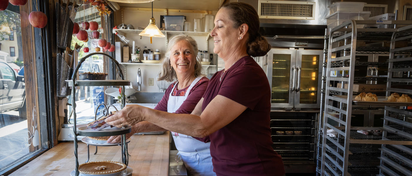 The owner of Moms Pie House and her daughter arrange pies in the front window.