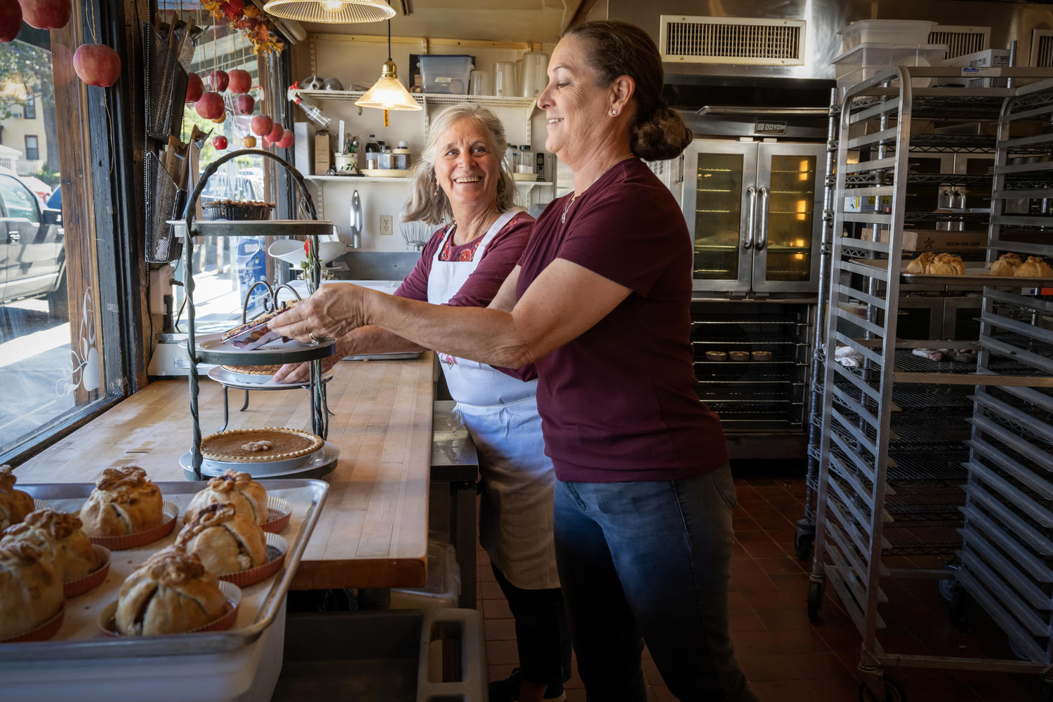 The owner of Moms Pie House and her daughter arrange pies in the front window.