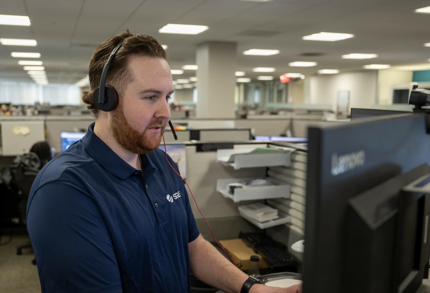 David in front of his computer, smiling because he enjoys his job.