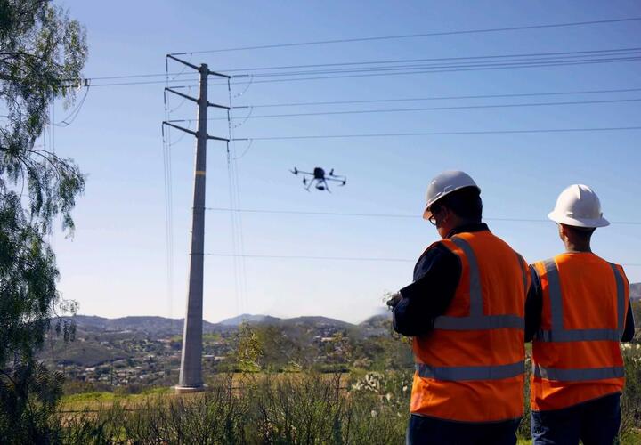 Workers examining transmission lines using drone photography