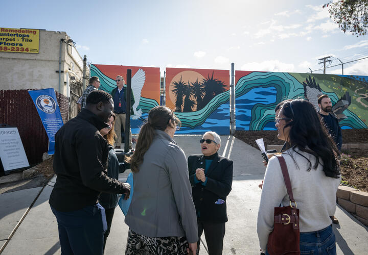 Mural unveiling event attendees mingle in front of the new mural.