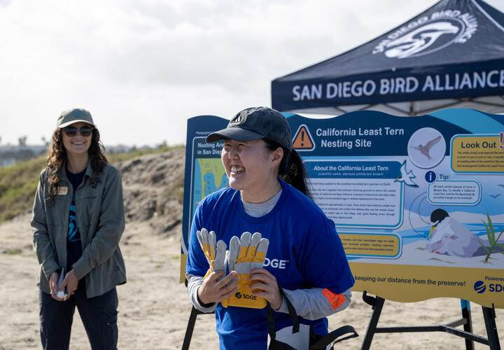 Asian female SDG&E employee smiles after receiving volunteer recognition gloves.