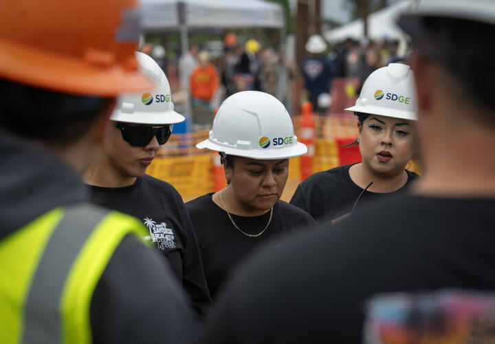 Three female gas crew members stand in a huddle with other SDG&E team members.