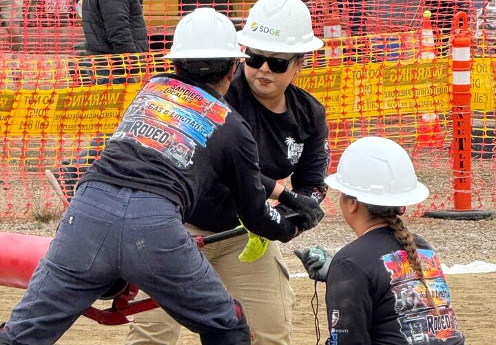 Three women wearing SDG&E hard hats participate in the lineworker rodeo.