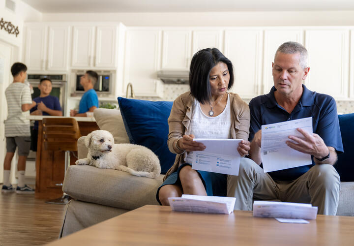 A couple sits on the couch looking at their SDG&E bill.