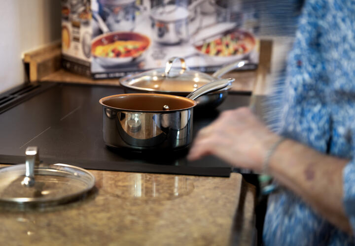 a person prepares a pot on an electric stove top.