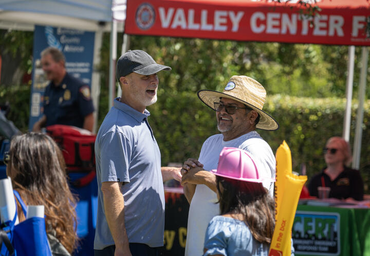 Scott Crider and SDG&E employee laugh during conversation at the Valley Center Wildfire Safety Fair