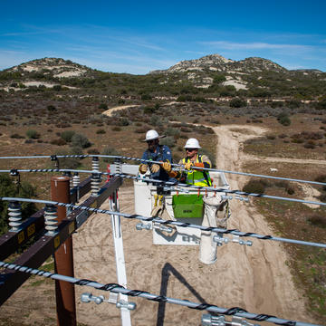 Two linemen in a bucket truck repairing power lines