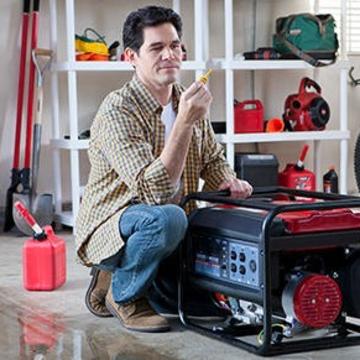 Man in a garage kneeling next to a generator