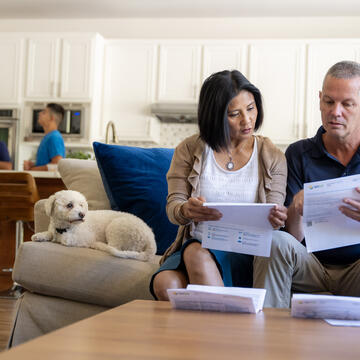 A man and a woman sitting on a couch in their home, reviewing their energy bill.