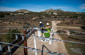 Two linemen in a bucket truck repairing power lines