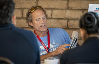 A male American red cross voulnteer demonstrates proper fire alarm installation techniques to new volunteers