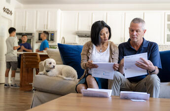 A man and a woman sitting on a couch in their home, reviewing their energy bill.