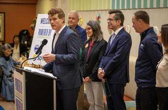Former Congressman and President of Citizens Energy, Joe Kennedy III stands at a podium, announcing EV grants to three San Diego County non-profits.