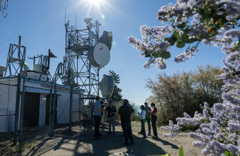 People stand in a gathering around weather-monitoring technology infrastructure.