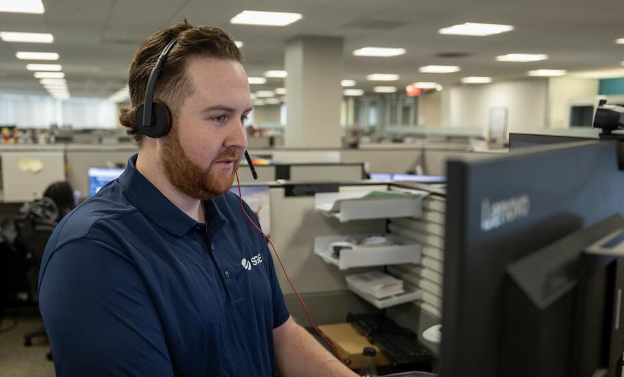 David in front of his computer, smiling because he enjoys his job.