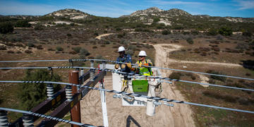 Two linemen in a bucket truck repairing power lines