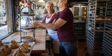 The owner of Moms Pie House and her daughter arrange pies in the front window.