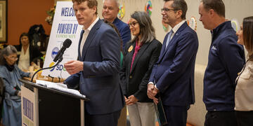 Former Congressman and President of Citizens Energy, Joe Kennedy III standing at a podium announcing the donation of EVs to three San Diego County non-profits. 