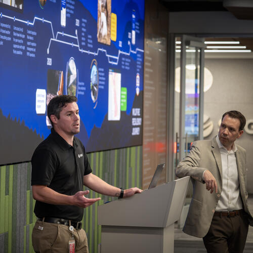 SDGE Communications Manager, Alex Welling, delivers opening remarks in front of a large screen at the media event.