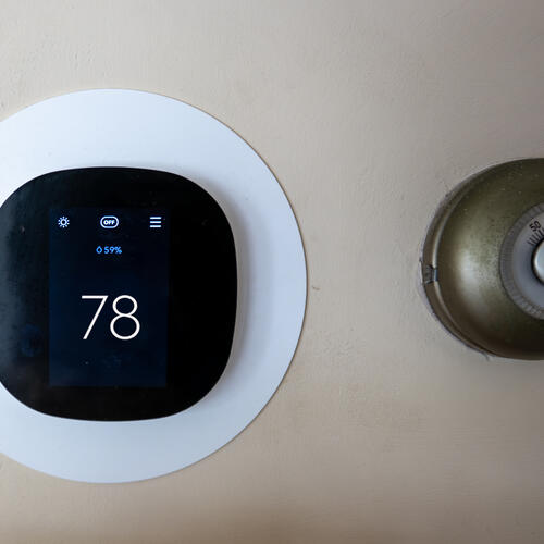 A photo of a modern thermostat, set to 78 degrees, alongside an older one.