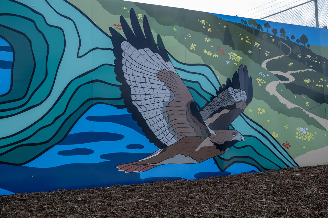 A section of the mural, showing an eagle flying over ocean and scenic landscape.